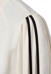 Weißer Stoff mit beigen und schwarzen vertikalen Streifen an einer gerafften Ärmel-Schulternaht.