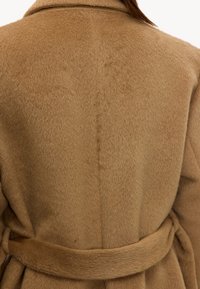 Manteau couleur chameau avec une finition douce et texturée, doté d'une taille ceinturée et d'un col à revers, vu de dos.