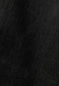 Gros plan sur un tissu en denim noir montrant une texture en armure diagonale et des variations subtiles de nuances.