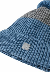 Szykowna czapka dzianinowa w niebiesko-szare paski z fakturowanym prążkowanym wzorem, z pomponem na górze i małą szaro-skalą naszywką z logo.