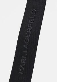 Cinturino nero texturizzato con il marchio in rilievo "KARL LAGERFELD", che presenta un design elegante e una sensazione di robustezza.