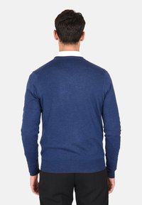 Maglione lavorato a maglia blu con scollo rotondo, maniche lunghe e polsini a coste. Texture liscia, silhouette aderente e senza motivi visibili.