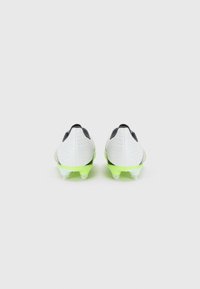 Des crampons de football avec un dessus texturé blanc et des accents noirs, et une semelle vert vif. Le design inclut des pointes coniques pour la traction.