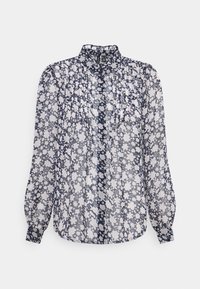 Blouse bleu marine transparent avec motif floral blanc, manches longues bouffantes, poignets froncés et col montant à volants avec plis sur le devant.