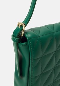 Prošívaná zelená kožená kabelka se strukturovaným tvarem, vybavená zlatým kováním s přezkou a úzkým ramenním popruhem.