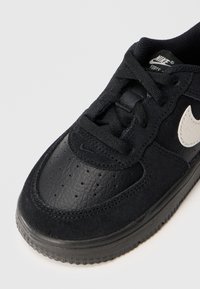 Sneaker nera con una combinazione di suede testurizzato e pelle liscia. Punta arrotondata, perforazioni sulla parte anteriore della scarpa, con un accento del logo bianco.