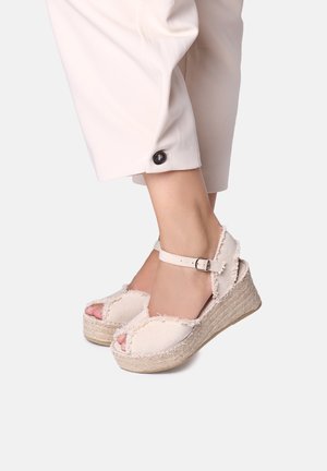 White espadrille wedges with a textured fabric upper, peep toe design, ankle strap with buckle, and woven jute platform.