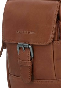 Borsa a tracolla in pelle marrone con patta, chiusura con fibbia metallica e logo "GREEN BURRY" in rilievo. Presenta una texture liscia e dettagli cuciti.