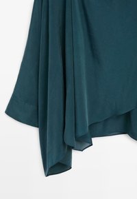 Tannengrün drapierte Stoffe mit weicher Textur, asymmetrischen Säumen und glatten, fließenden Falten für ein entspanntes Design.
