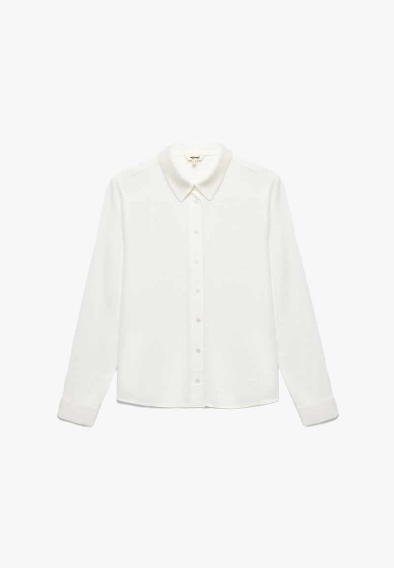 Camisa blanca de manga larga hecha de tela suave, con un cuello clásico y un cierre frontal de botones. Las muñecas tienen cierres de botón.