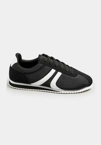 Black athletic shoes with a smooth fabric upper and white accents. Features a rounded toe, lace-up closure, and textured rubber sole.