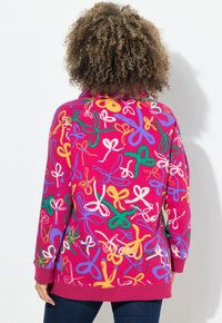 Felpa fucsia con stampa di fiocchi colorati, maniche lunghe, polsini e orlo a coste. Il materiale sembra morbido e testurizzato.