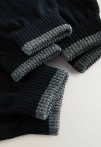 Chaussettes en tricot noires avec des poignets côtelés gris foncé. Fabriquées en matériau doux, elles présentent une surface texturée et un maintien confortable au niveau de la cheville.