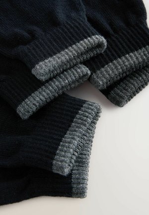 Schwarze Stricksocken mit dunkelgrauem Rippbund. Hergestellt aus weichem Material, mit einer strukturierten Oberfläche und einer engen Passform am Knöchel.