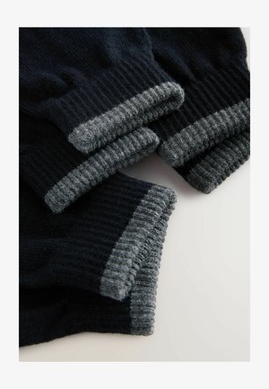 Calcetines de punto negros con puños acanalados en gris oscuro. Fabricados con materiales suaves, presentan una superficie texturizada y un ajuste ceñido en el tobillo.