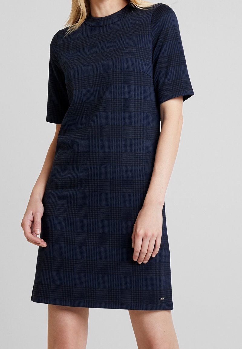 Robe navy blue à manches courtes avec un motif en grille, décolleté rond et coupe droite. Tissu lisse avec des détails de couture minimalistes.