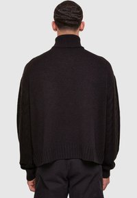 Maglione nero lavorato a maglia con colletto alto, taglio morbido e maniche a treccia testurizzate. L'orlo e i polsini a coste aggiungono un tocco di eleganza.
