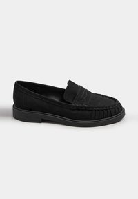 Mocassino in suede nero con suola piatta in gomma, caratterizzato da una punta in stile mocassino cucita e una fascia decorativa frontale.