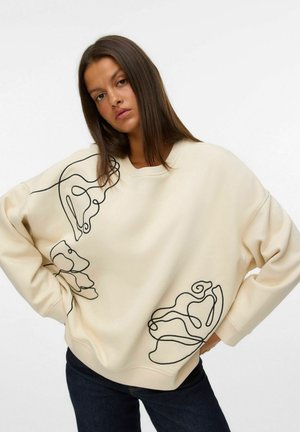 Felpa oversize crema con design astratto nero sulla parte anteriore e sulle maniche. Realizzata in tessuto morbido, presenta un colletto rotondo e maniche lunghe.