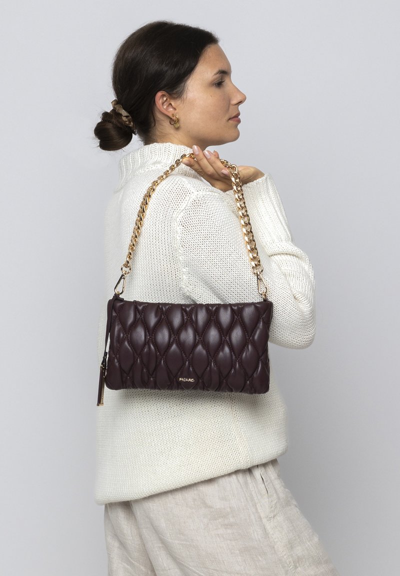 Gestepptes burgunderfarbenes Handtasche mit einem goldenen Kettenriemen, mit einer glatten Ledertextur und einem goldenen Logo-Detail.