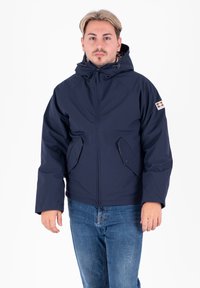 Giacca isolante blu navy con cappuccio, dotata di zip frontale, due tasche laterali e fodera interna a scacchi. Tessuto morbido.