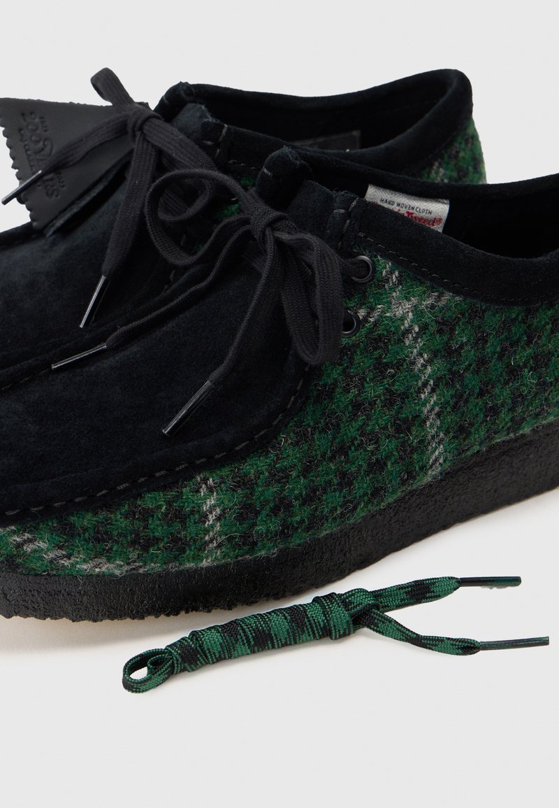 Green and black patterned shoes made of felted wool with suede accents; includes black laces and matching green patterned lace.