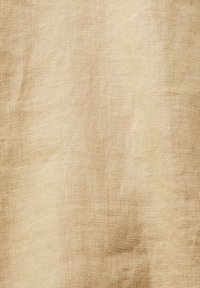 Tissu en lin tissé beige avec texture visible et plis subtils, créant un aspect naturel et rustique.