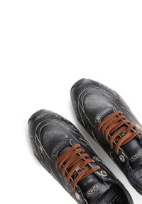 Svart lær sneakers med teksturert overflate, brune semskede snører, rund tå og kontrasterende hvite sømdetaljer. Syntetisk metallisk akenter synlige.