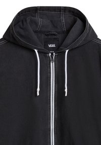 Svart huva jacka med framdragkedja, vita snörningar och kontrasterande söm detaljer. Har en modern, enkel design.