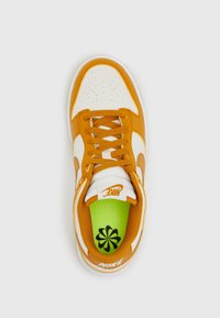 Oranžovo-bílá teniska s kulatou špičkou, horní část z tkaniny, s perforacemi a šněrováním. Zelená stélka zdobená černým květinovým vzorem.