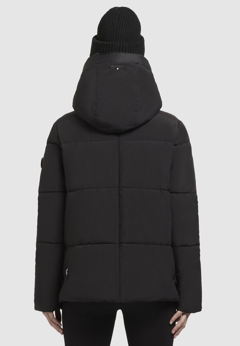 Schwarze Steppjacke mit Kapuze, ausgestattet mit gesteppten Abschnitten, hohem Kragen und elastischen Bündchen. Weiche Textur und minimales Markenlabel.