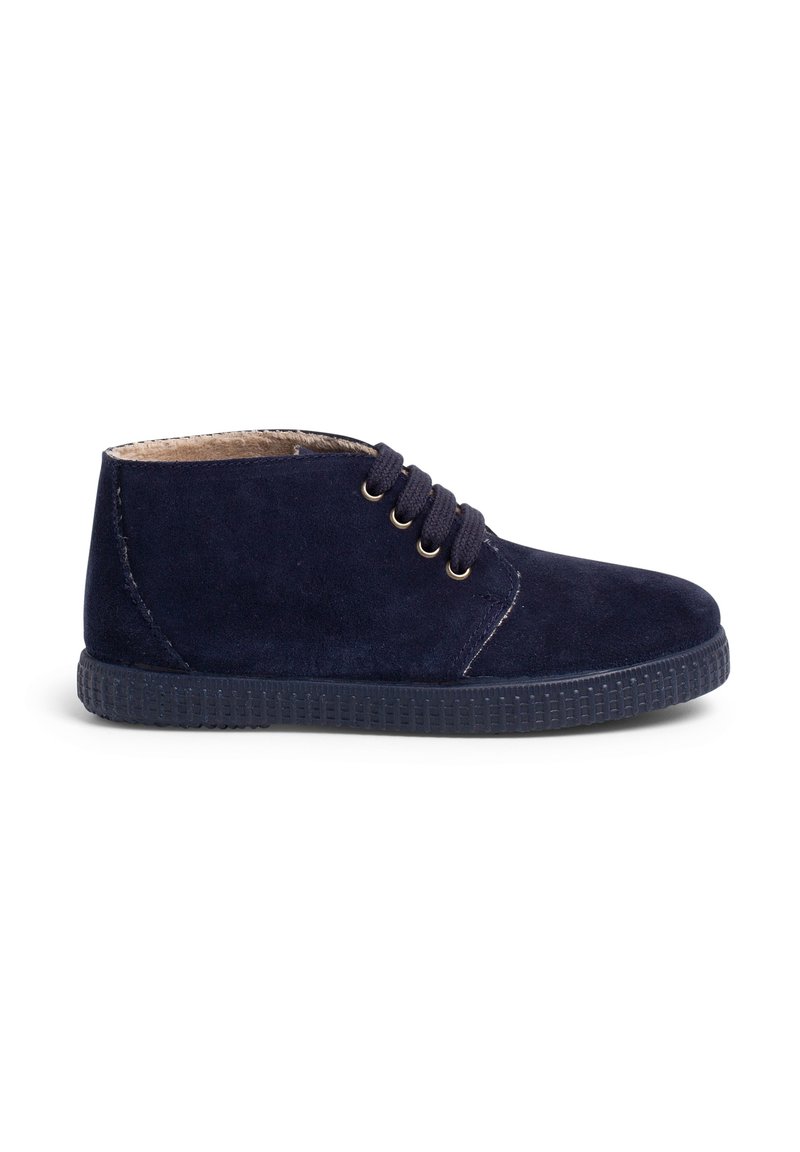 Botín de ante azul marino con punta redonda, suela de goma texturizada y cuatro ojales para los cordones. Diseño simple con detalle de costura.