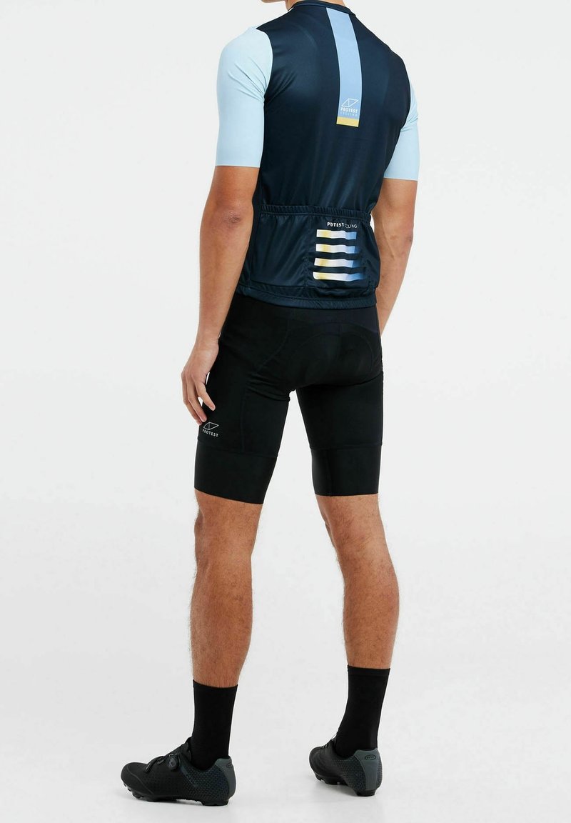Maillot de cyclisme à manches courtes en bleu foncé et bleu clair avec des accents rayés ; associé à un cuissard rembourré noir et des chaussures de cyclisme.