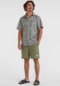 Patterned short-sleeve shirt in green and gray hues, paired with olive green shorts. The shirt features a button-up front and collar.