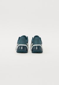 Pantofi de sport teal cu un material texturat, talpă flexibilă și accente gri. Prezintă un guler căptușit și un tab de tragere în spate pentru o purtare ușoară.