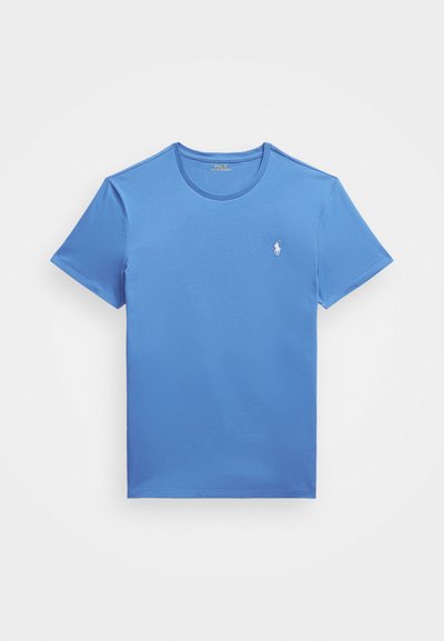 Blå bomulls t-shirt med korta ärmar och rundad hals. Har en liten vit broderad logotyp på vänster bröst. Slät textur.