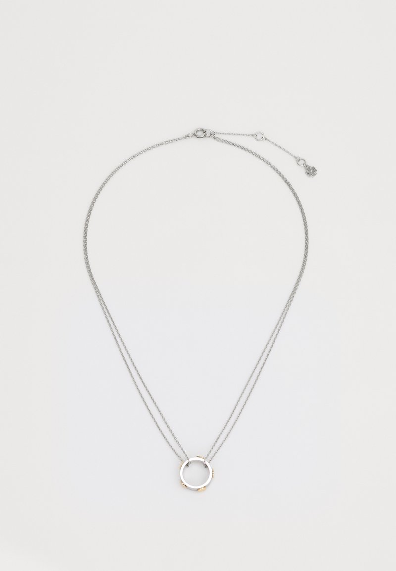 Collana a strati in tonalità argento con un pendente circolare caratterizzato da accenti dorati e una catena testurizzata, chiusa da un gancio.