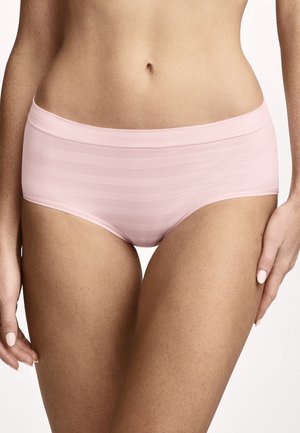 Torso y parte superior de las piernas de una mujer con ropa interior hipster sin costuras a rayas de color rosa claro sobre un fondo liso.