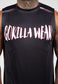 Zwarte sportieve tanktop met "GORILLA WEAR" in bold witte letters, met een stippenpatroon en grijze accenten op de schouders.