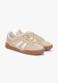 Beige sneakers gemaakt van suede en mesh, met witte strepen, ronde neus, vetersluiting en een rubberen gumzool.