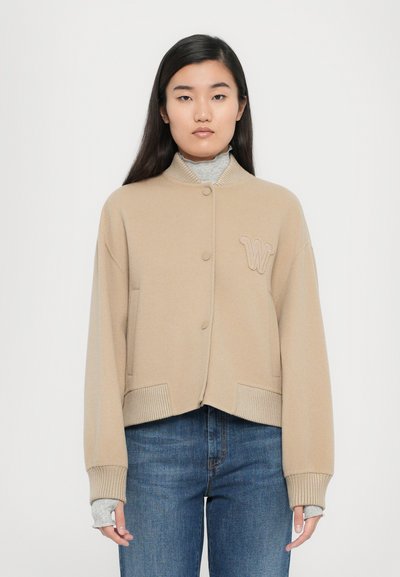 Cardigan accorciato beige con colletto e polsini a coste, dotato di chiusura centrale con bottoni e un accento ricamato con la lettera "W".