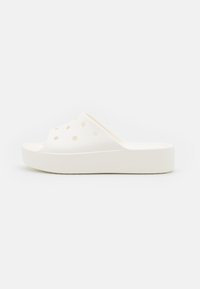 Vita skum slip-on sandal med upphöjd plattformssula och runda ventilationshål på den övre remmen, visas i sidoprofil.