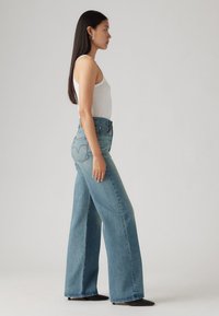 Hoge taille, wijde jeans in lichtblauwe denim. Voorzien van voorzakken, een knoopsluiting en een klassieke vijfzakkenontwerp.