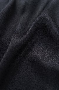 Schwarzer Stoff mit einer glatten, strukturierten Oberfläche, der subtile Variationen im Farbton und in der Tiefe aufweist, feine Details zeigt und weich fällt.