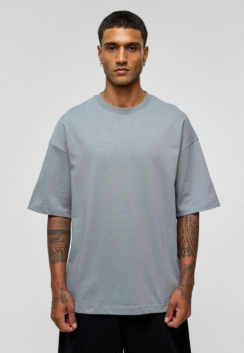 Grijze oversized t-shirt gemaakt van zachte stof, met een ronde halslijn en korte mouwen. Minimalistisch ontwerp zonder zichtbare patronen.
