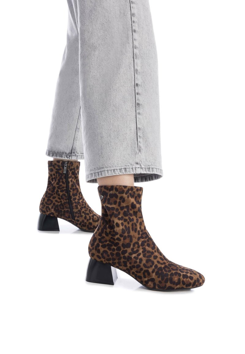 Botas hasta el tobillo con estampado de leopardo, hechas de tela suave, con punta cuadrada y un tacón grueso negro. Detalle de cremallera en el lateral.