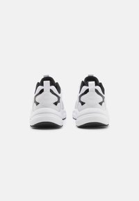 Valkoiset ja mustat lenkkitossut, joissa on verkkopäällinen, muotoillut yksityiskohdat ja pehmustettu pohja. Niissä on vahvistetut kantapään nyörit helpottamaan pukemista.