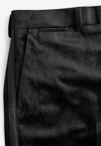 Pantaloni neri realizzati in un tessuto morbido, caratterizzati da una superficie liscia, fronte piatto, vita singola e dettagli laterali in un materiale a contrasto.