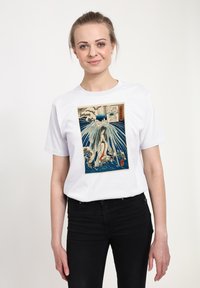 Bílé tričko s obrázkem ženy obklopené vlnami a mraky, v modré, červené a béžové barvě, s japonským textem na motivu.