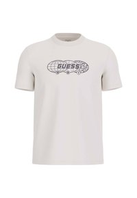 T-shirt di colore beige chiaro in cotone, con una stampa grafica che presenta la scritta "GUESS" e un design di un globo. Maniche corte e scollo rotondo.